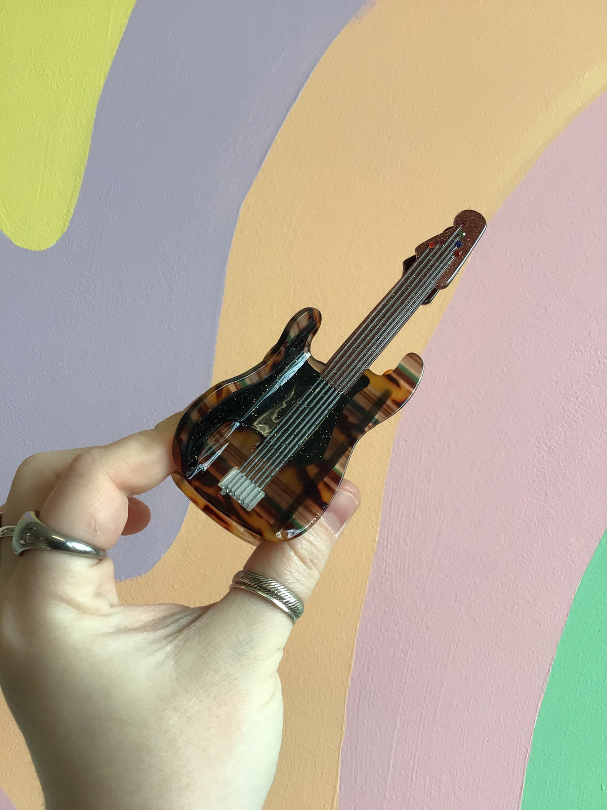 Brown electric guitar hair claw with dark fretboard and silver hardware details