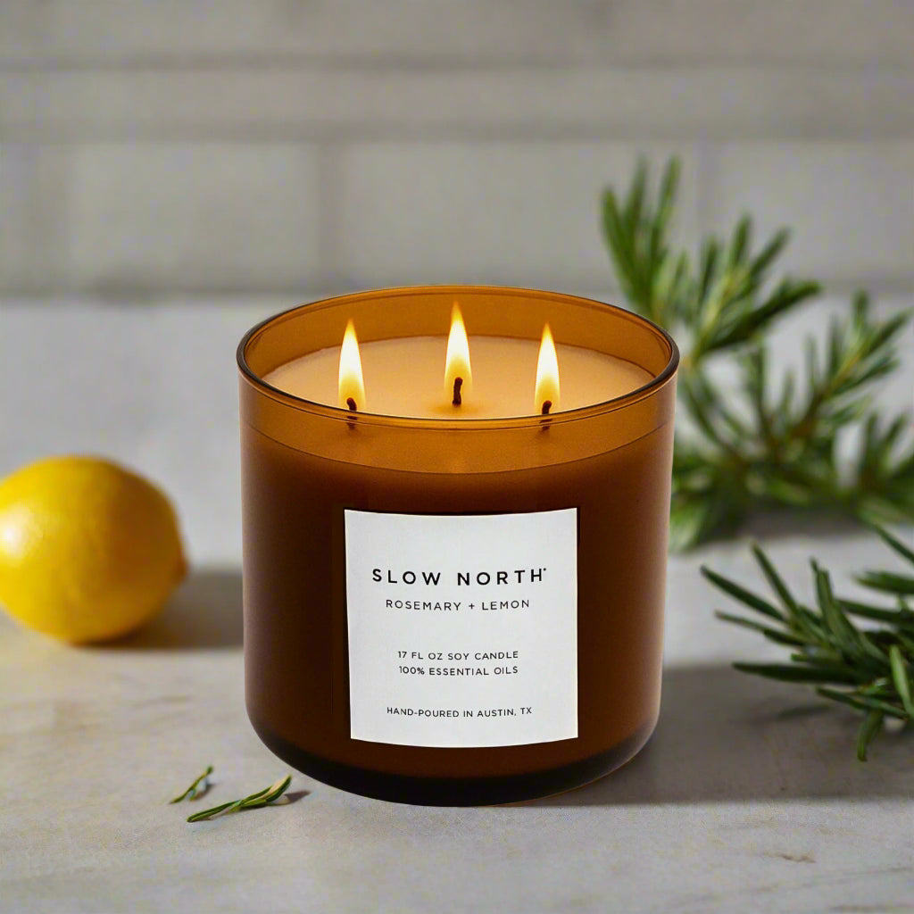 Brown 3-wick soy candle in glass jar with three lit flames and front label