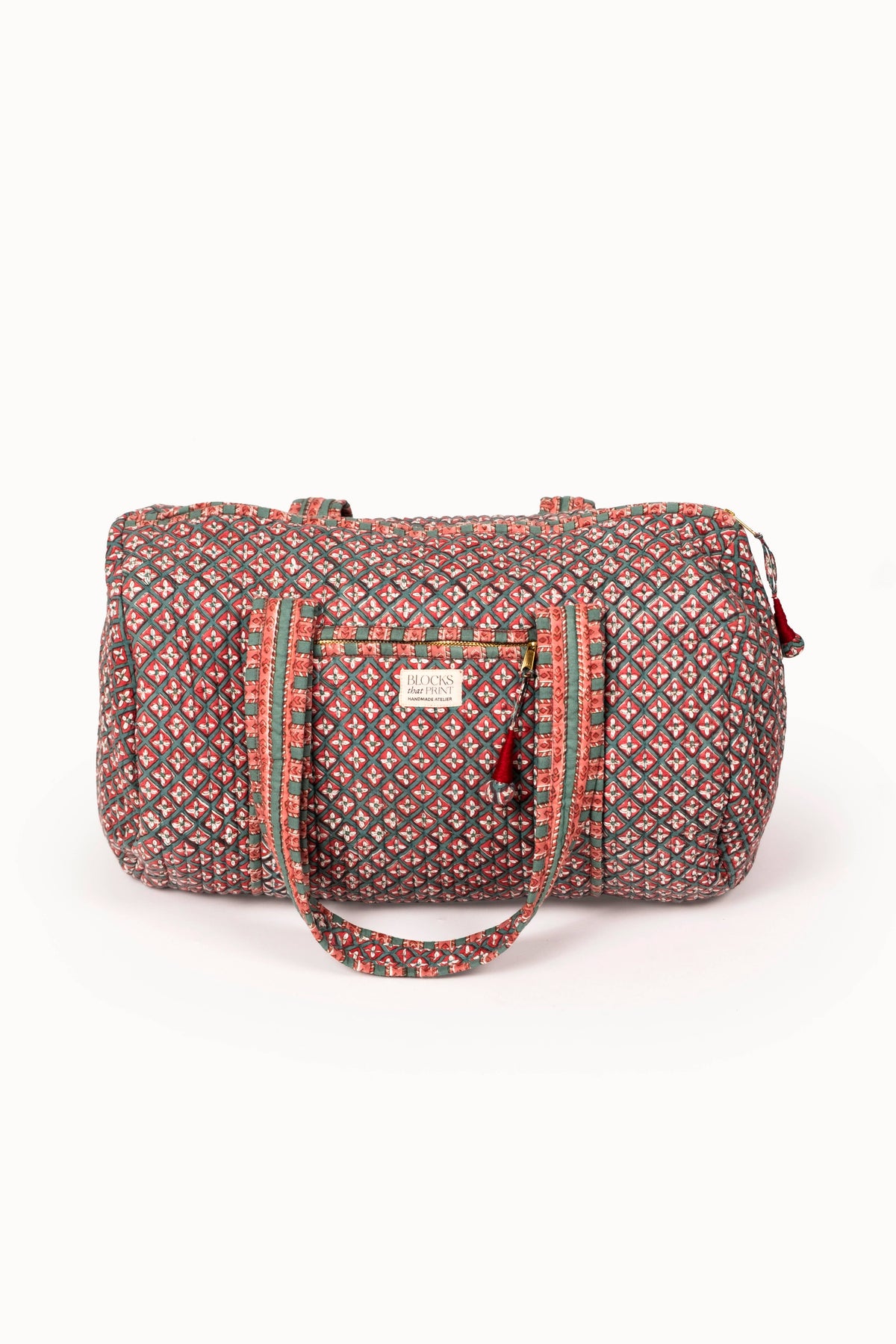 Quilted duffle bag with red-and-green block print, zip top, front pocket, strap