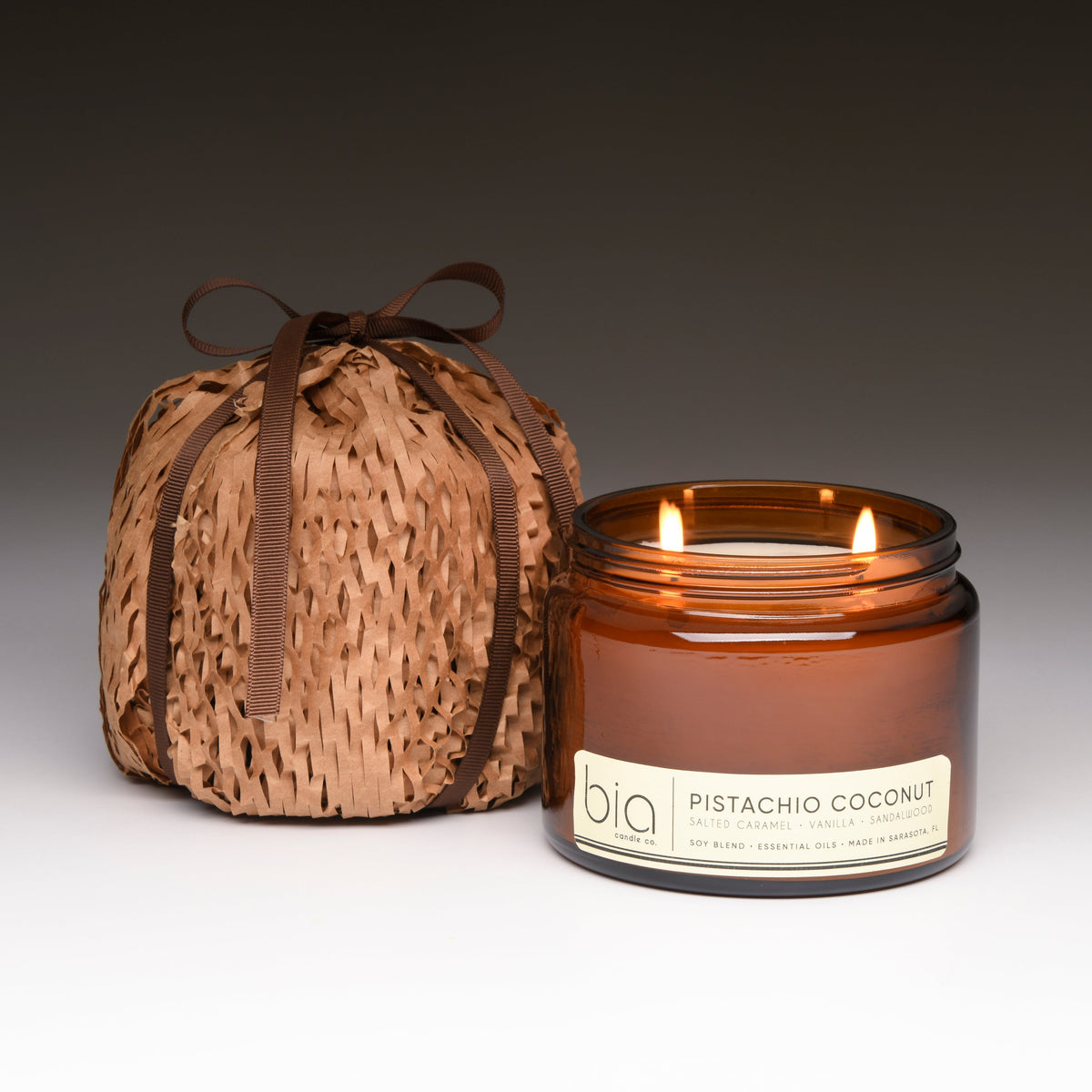 Amber soy blend candle in clear glass jar with lit wick, text label on front.