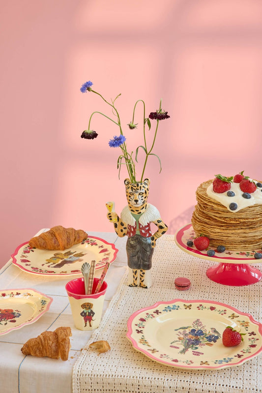 Melamine dinner plate with neon pink rim and colorful floral bird print on table