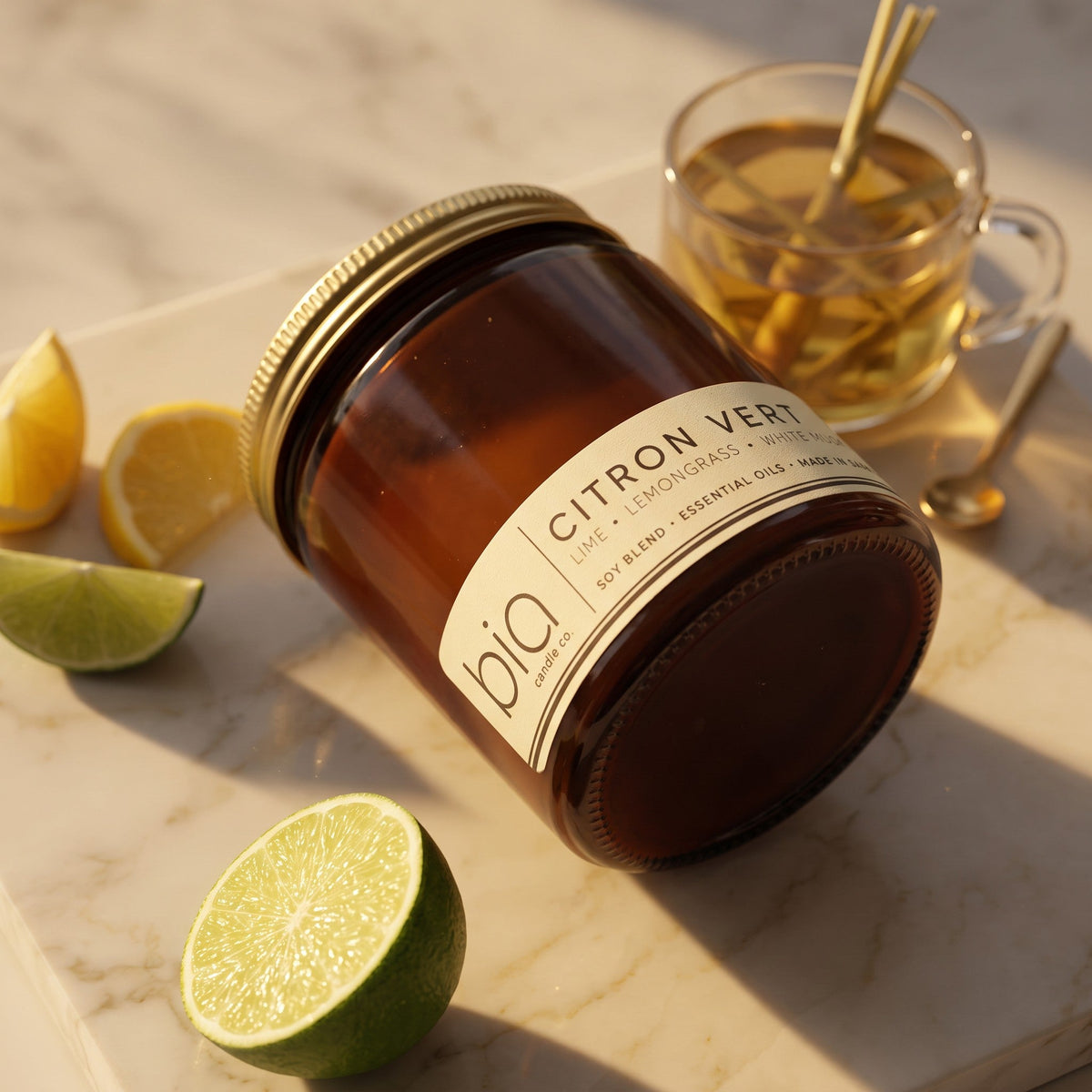Amber soy blend candle jar with cream Citron Vert label, with citrus wedges nearby.
