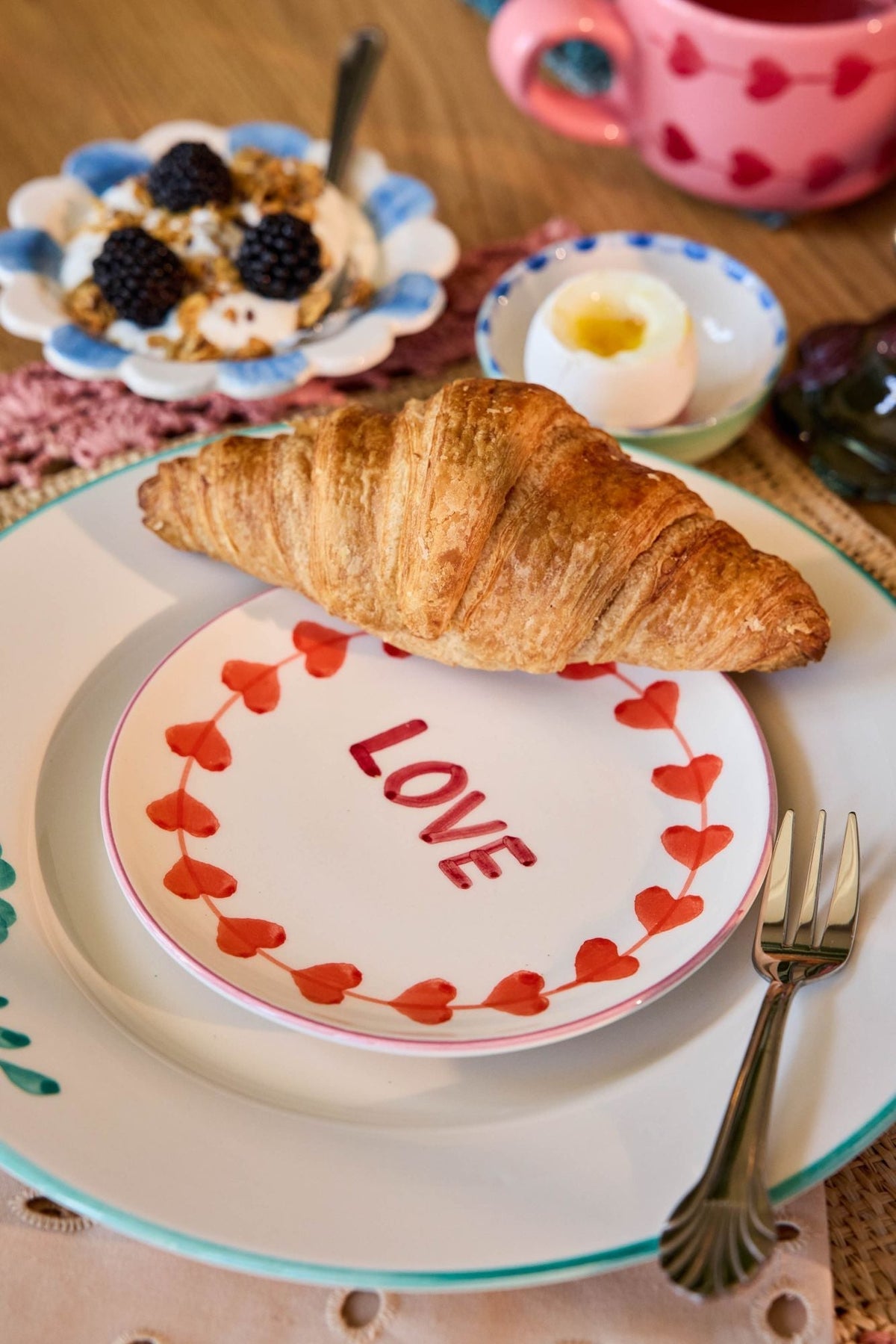 Round ceramic cake plate showing hand-painted LOVE in red on white with heart border