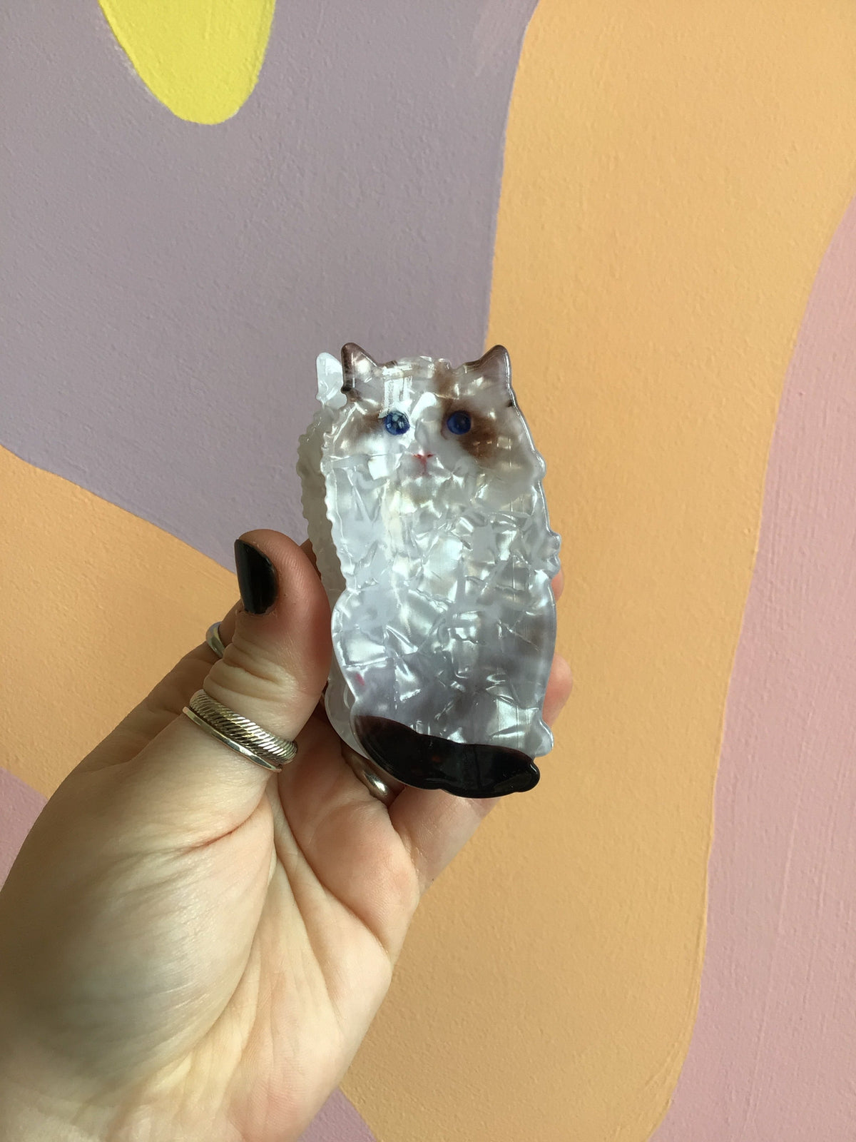 Cat hair claw with silver-toned face and blue eyes, held in hand