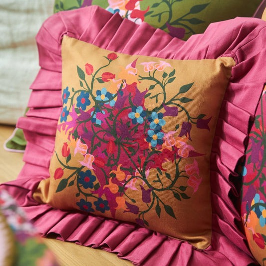 Pink ruffled pillow cover with tan front and multicolor floral illustration