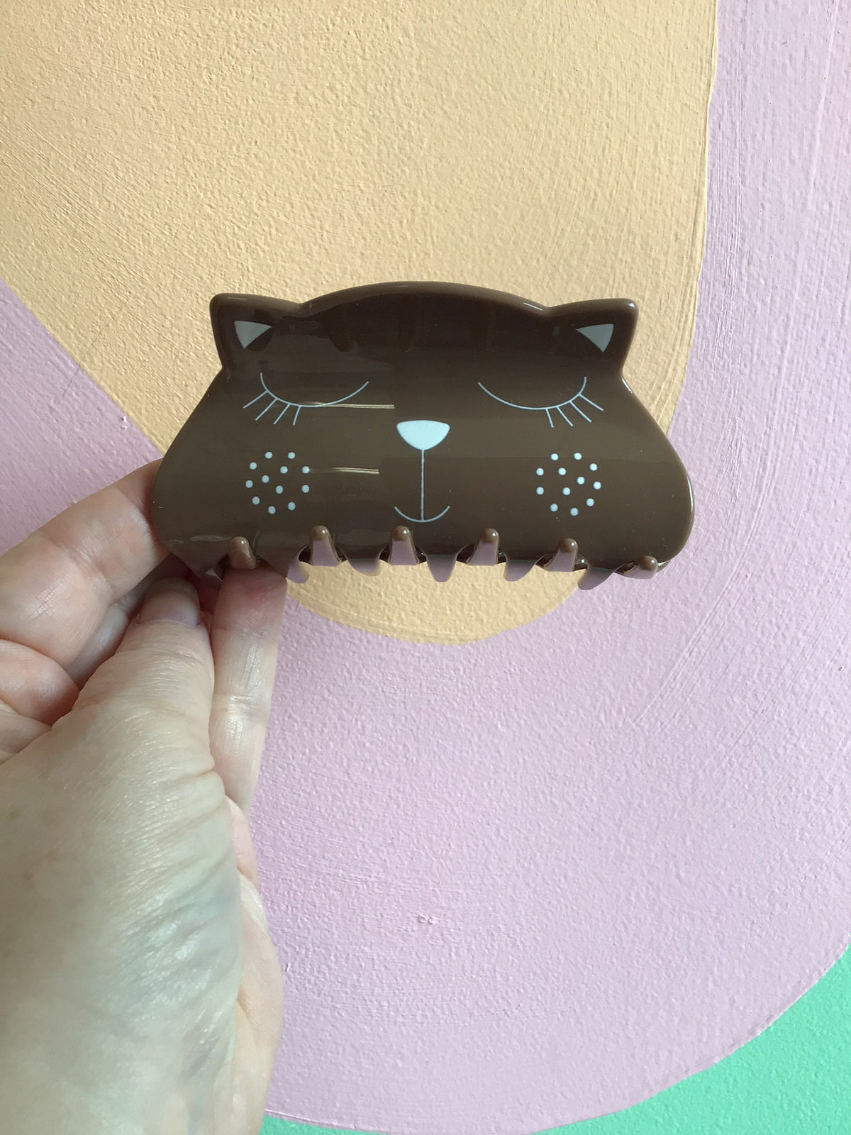 Dark brown kitty hair claw with closed-eye face and small spark dot details