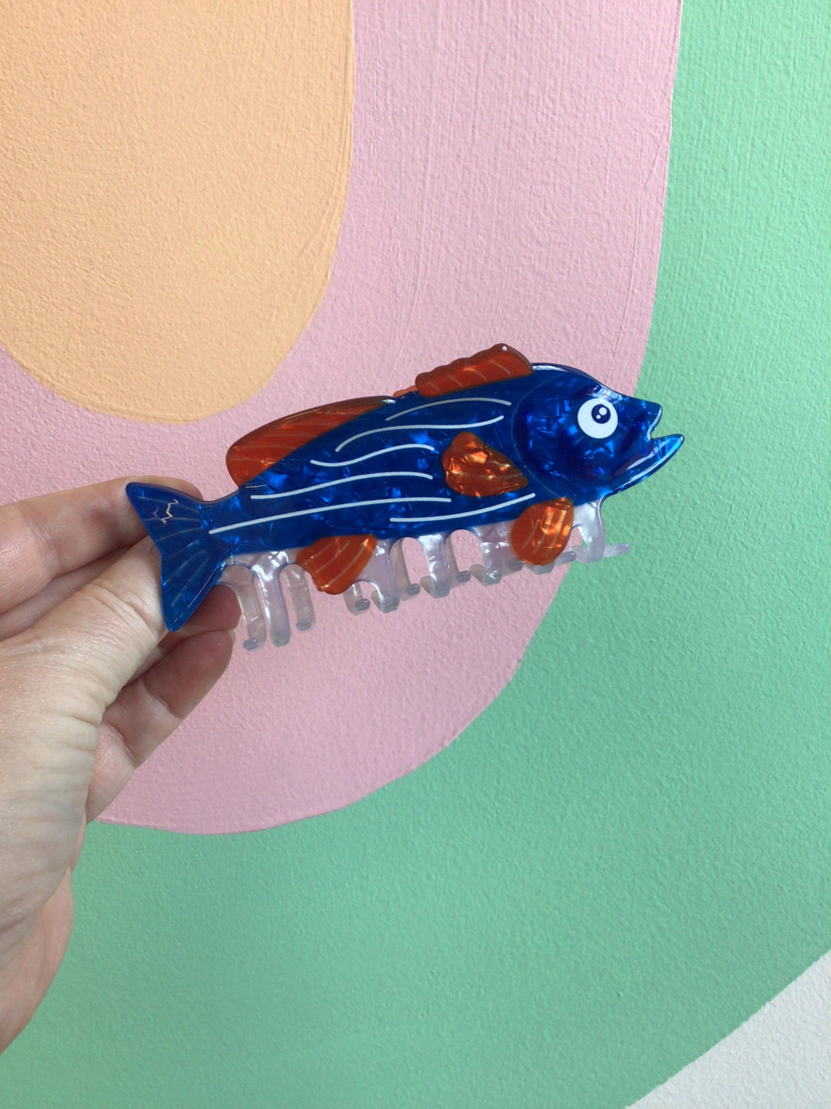 Blue fish hair claw with orange top and clear translucent comb teeth.