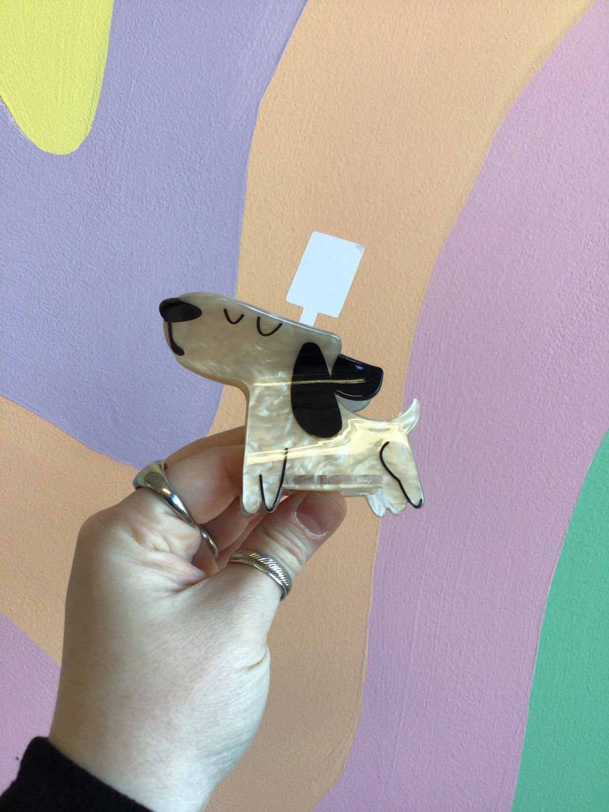Dog-shaped hair claw with black ears and cream body, held in a hand