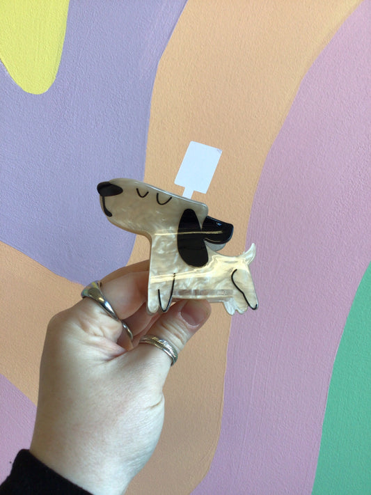 Dog-shaped hair claw with black ears and cream body, held in a hand