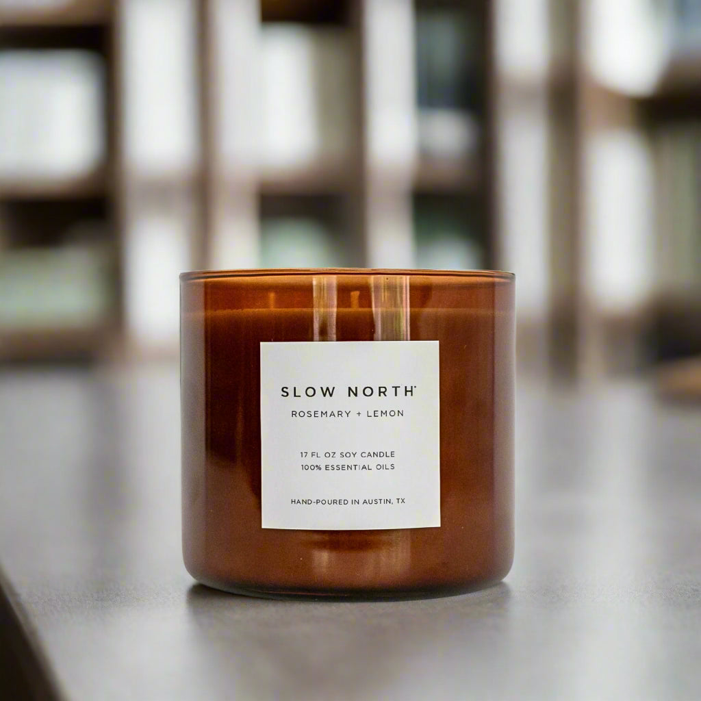 Brown 3-wick soy candle in glass jar with front label and one wick lit