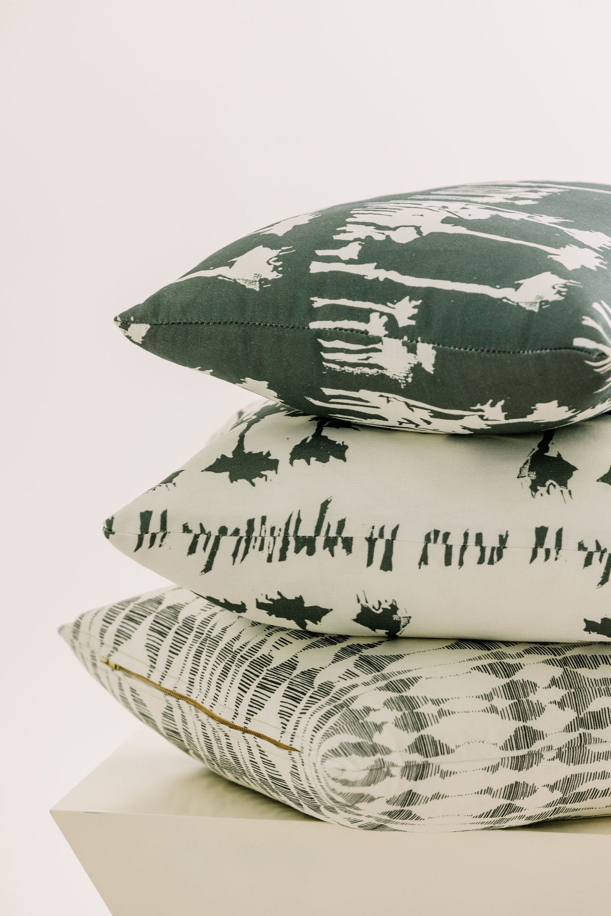 Stacked 16x20 pillows with dark-green splash and animal silhouette patterns