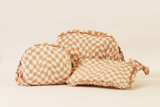 Handmade quilted pouch with flap, peach-and-white checkered fabric, gathered top and tassel.