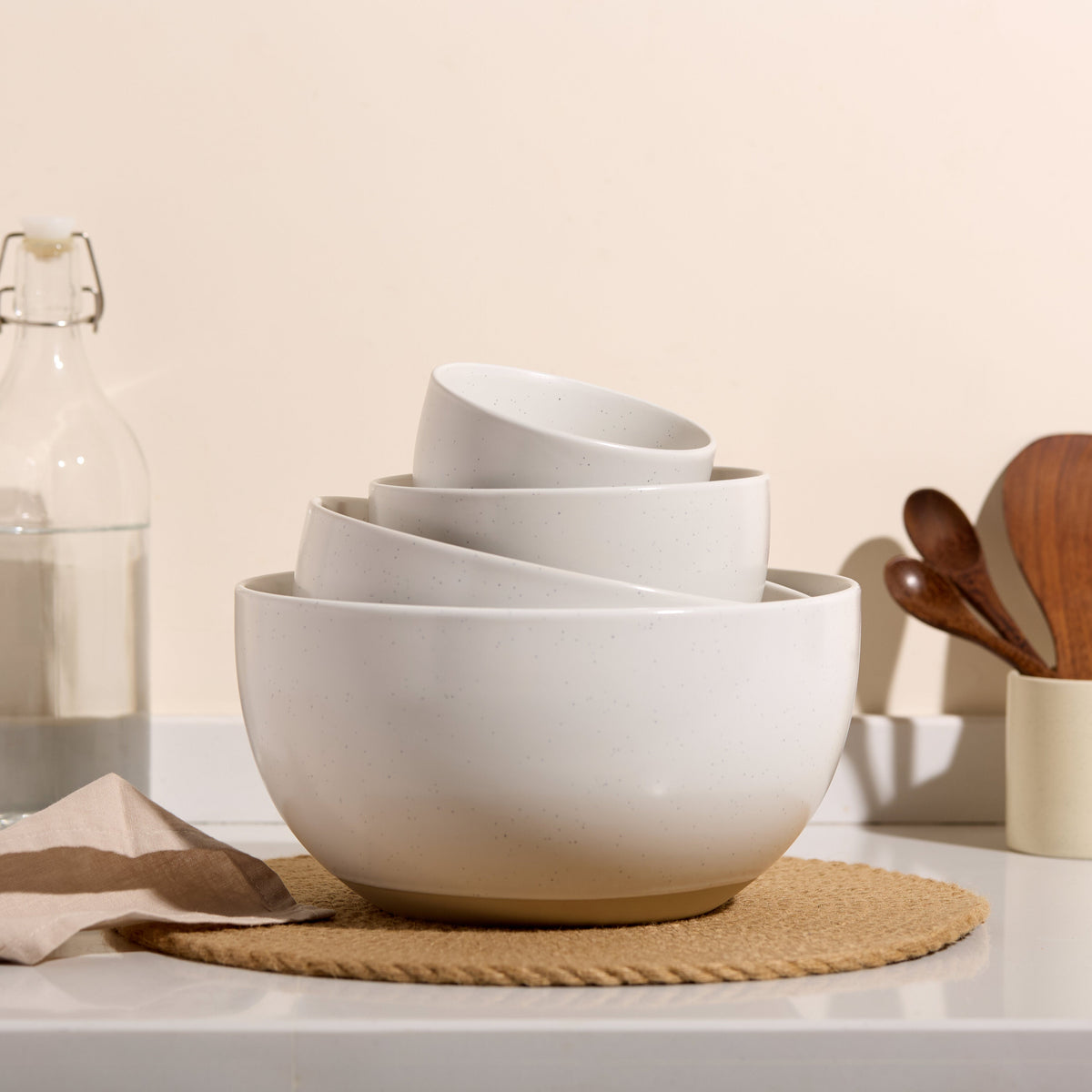 Set of 4 ceramic nesting bowls in speckled off-white, stacked on a neutral mat