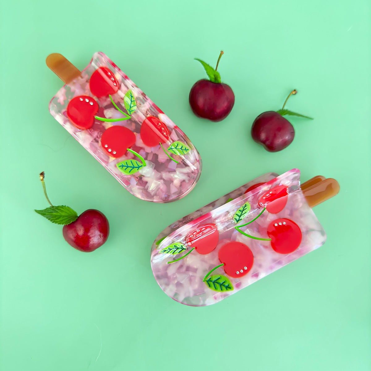 Set of cherry popsicle hair claws with translucent pink design, red cherries, and tan prongs