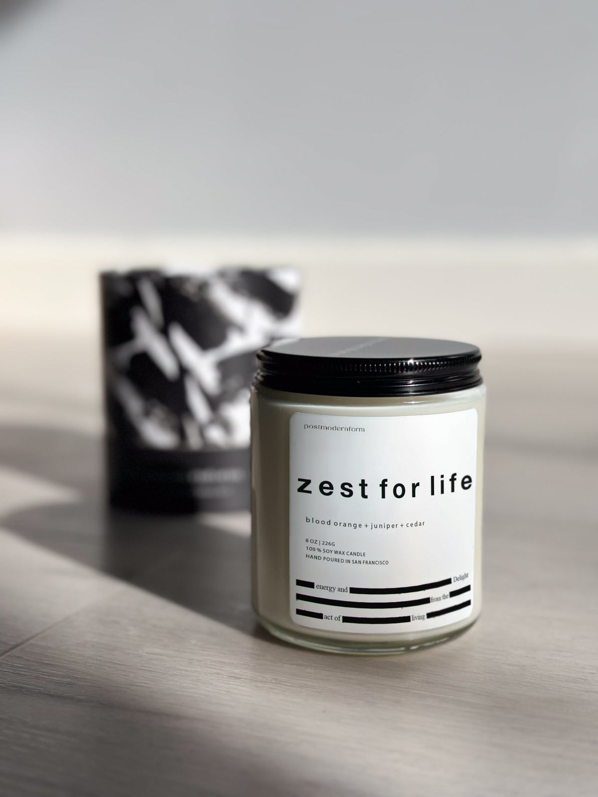 Zest for life candle in frosted jar with black lid, front label visible