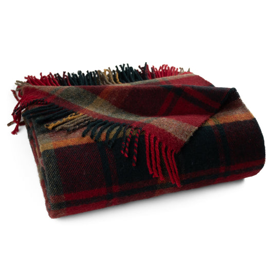 Folded lambswool throw blanket in dark red, tan, and green plaid with fringe border