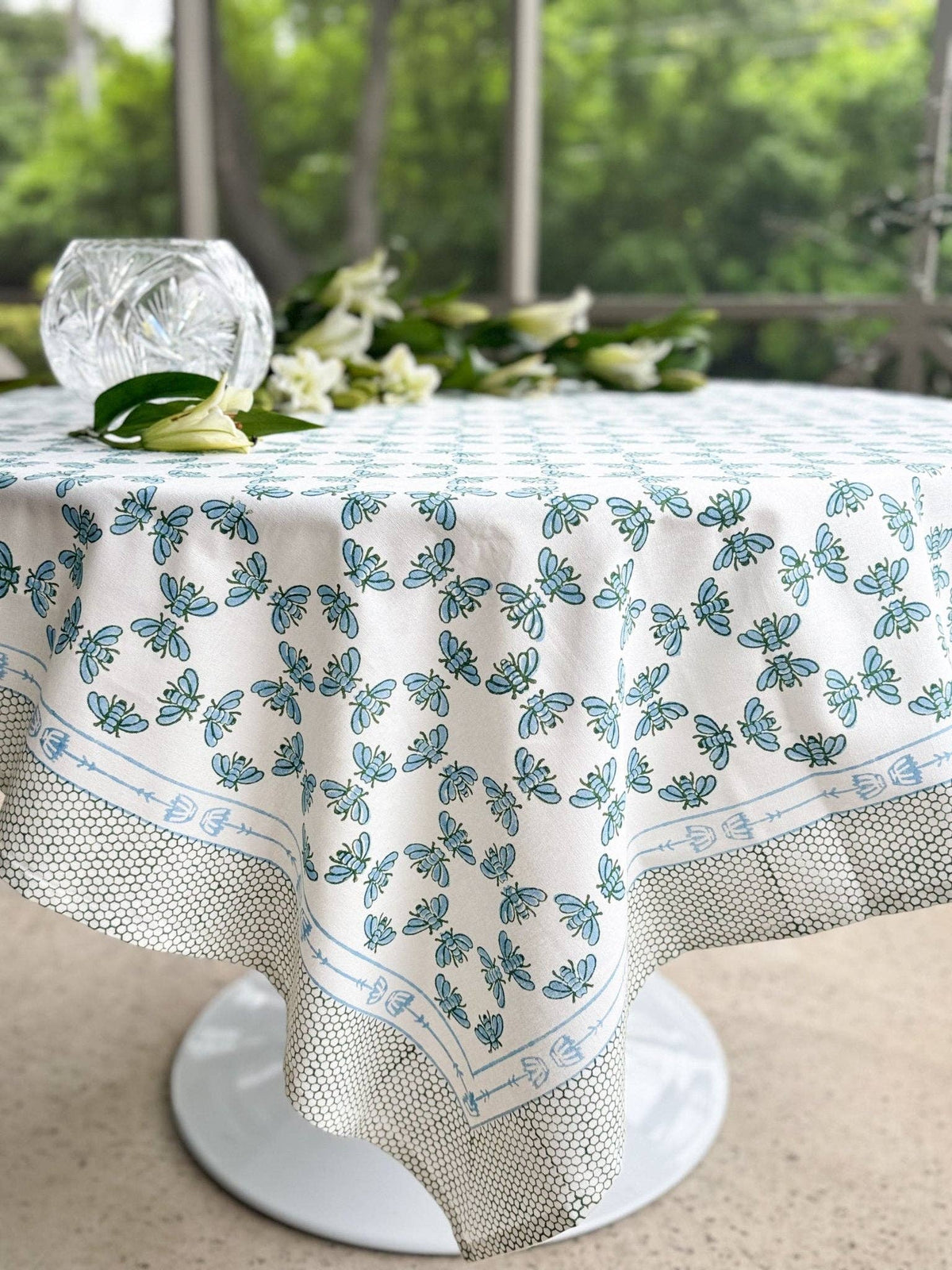 Table throw on tabletop with blue-and-sage floral print, plus textured mesh-style underside.