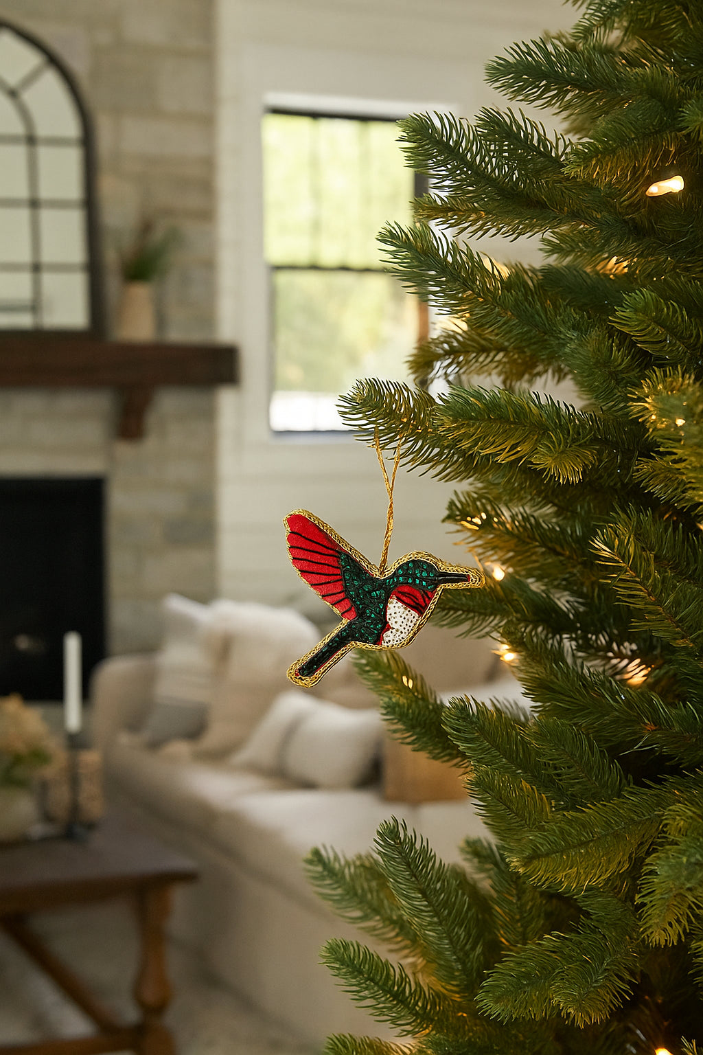 Hummingbird plush fabric ornament hanging on a Christmas tree, red and green embroidered detail