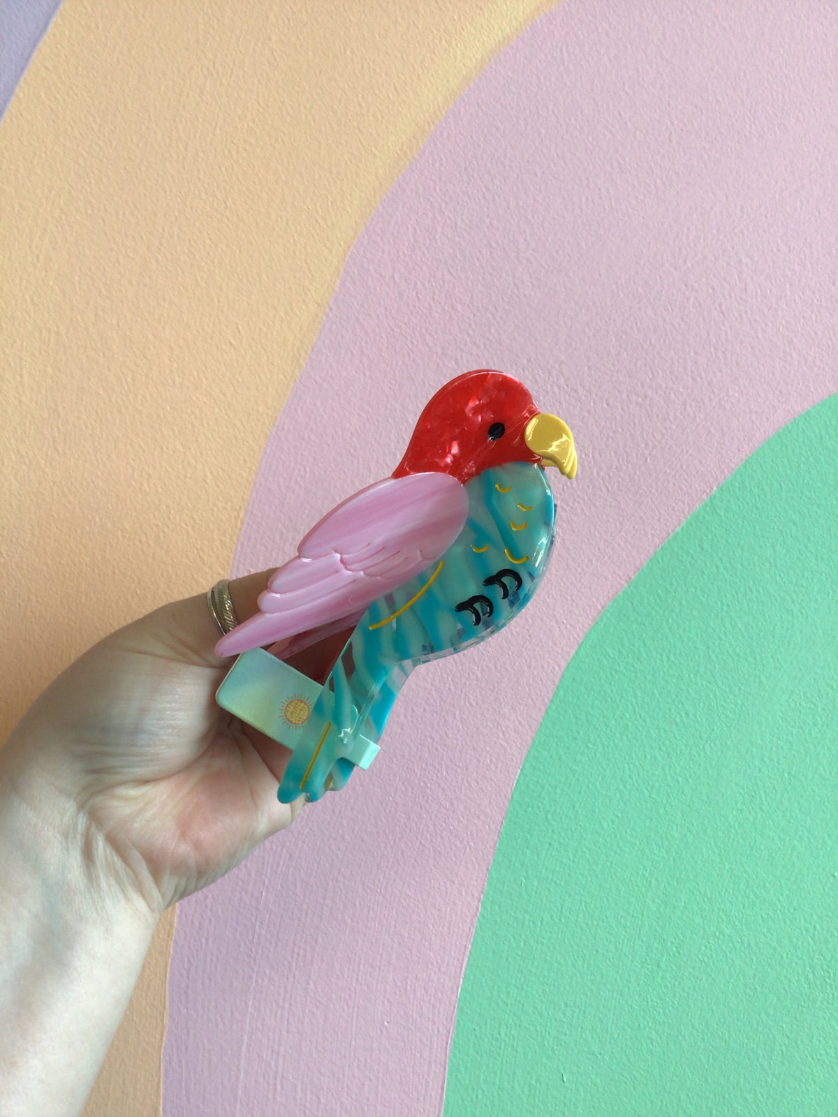 Teal and pink bird hair claw with red head and yellow beak