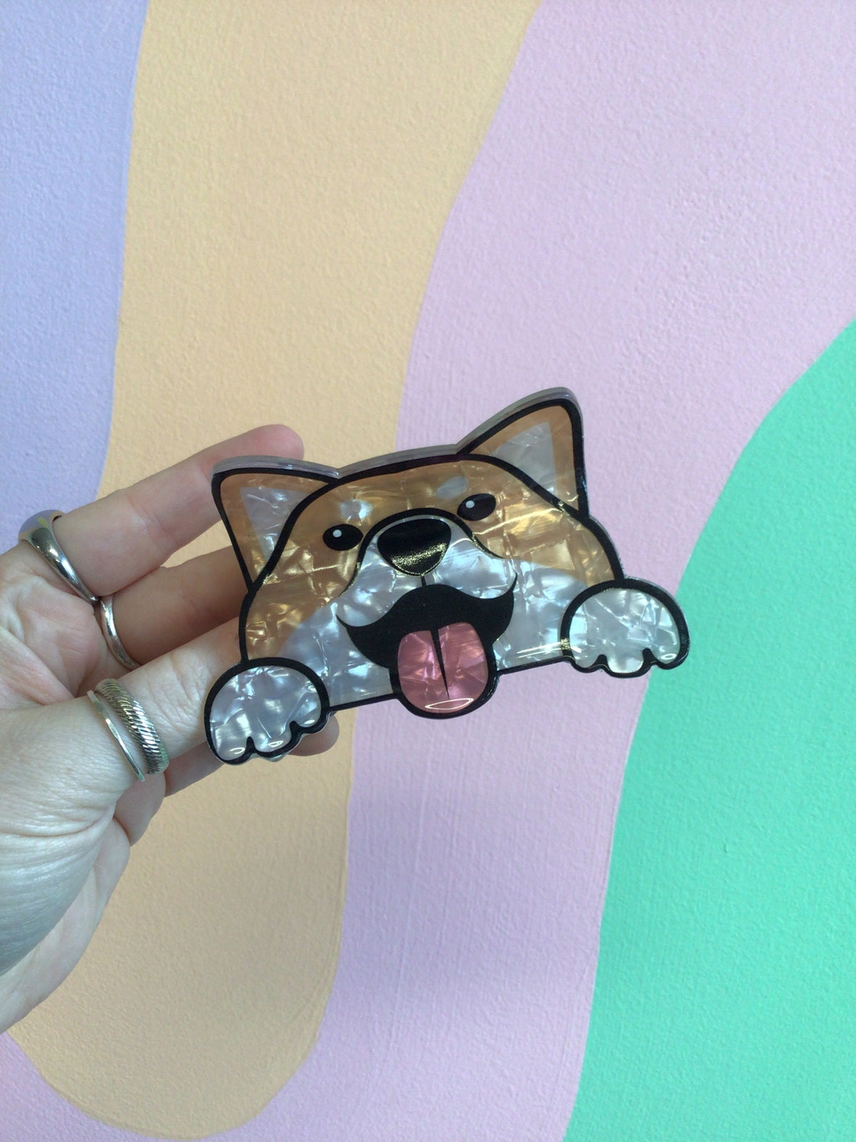Tan-and-black dog hair claw with tongue out, held in hand