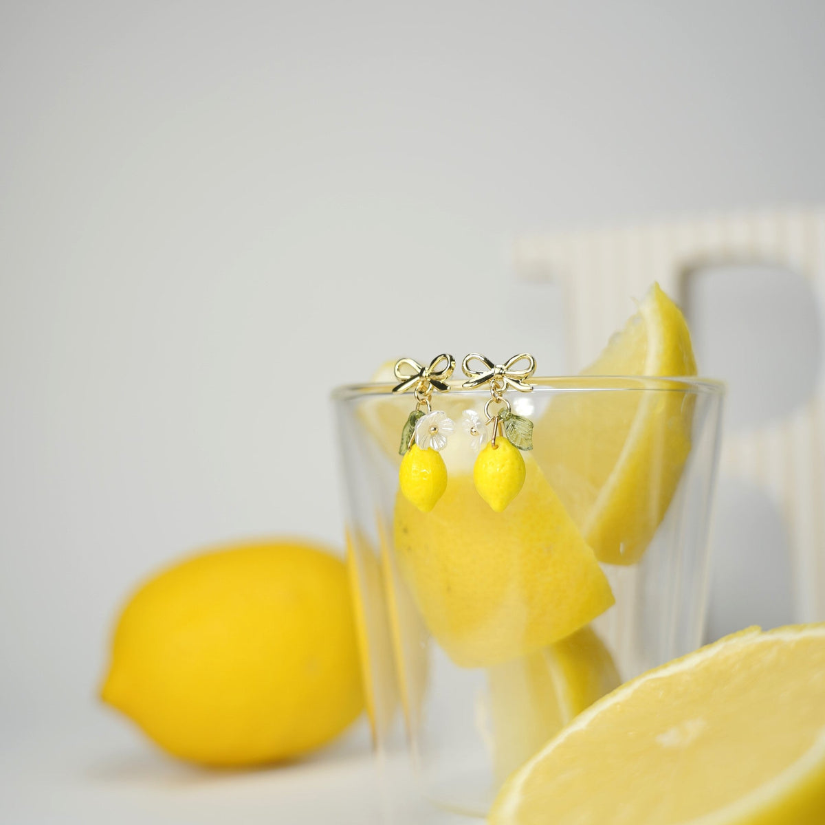 Pair of lemon dangle earrings with yellow lemon drops, green leaves, and gold hooks