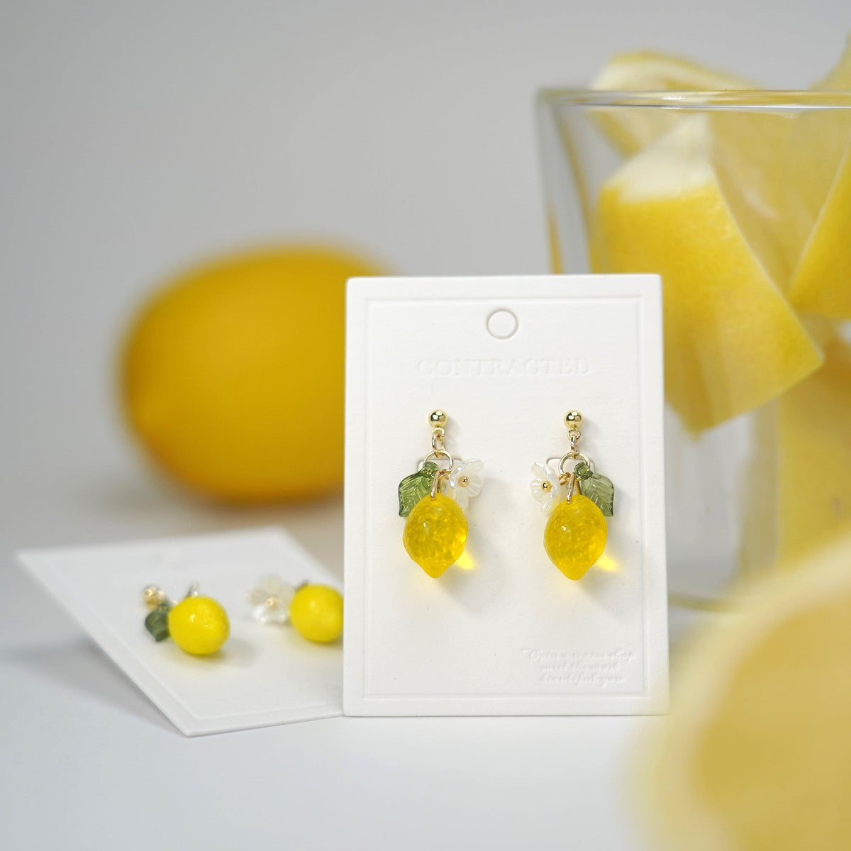Yellow lemon dangle earrings on card with green leaf details and gold-colored hardware