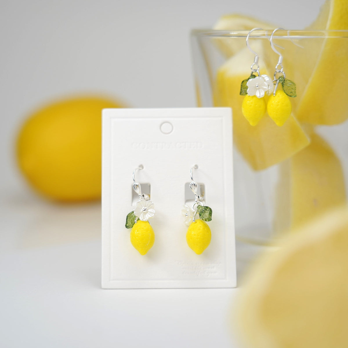 Lemon dangle earrings on card with yellow drops, green leaves, and clear stone flower accents