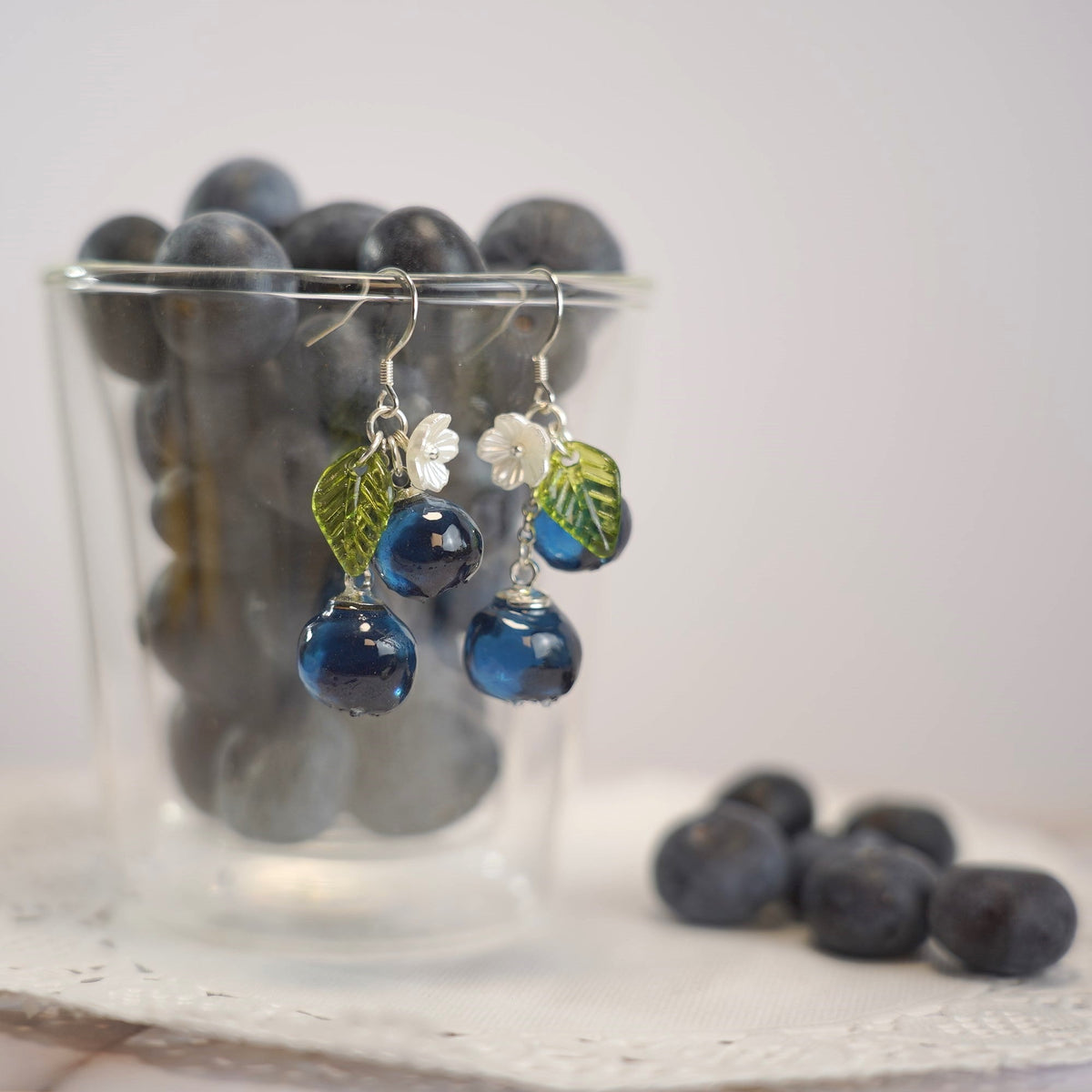 Blueberry cluster dangle earrings with blue resin berries, green leaves, and silver hooks
