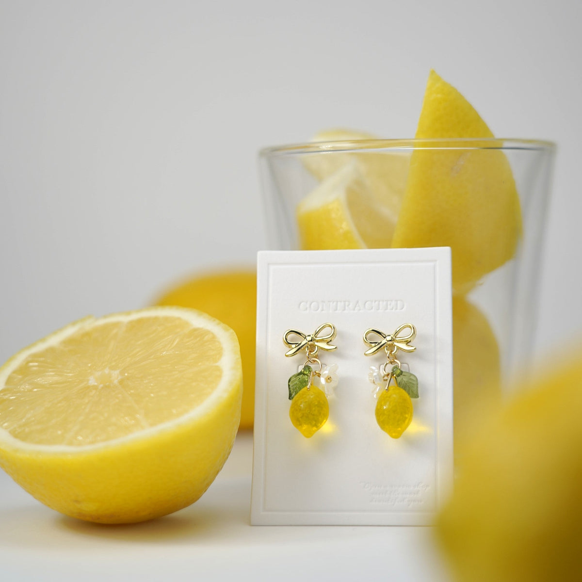 Gold dangle lemon earrings with two yellow lemon charms and green leaf accents