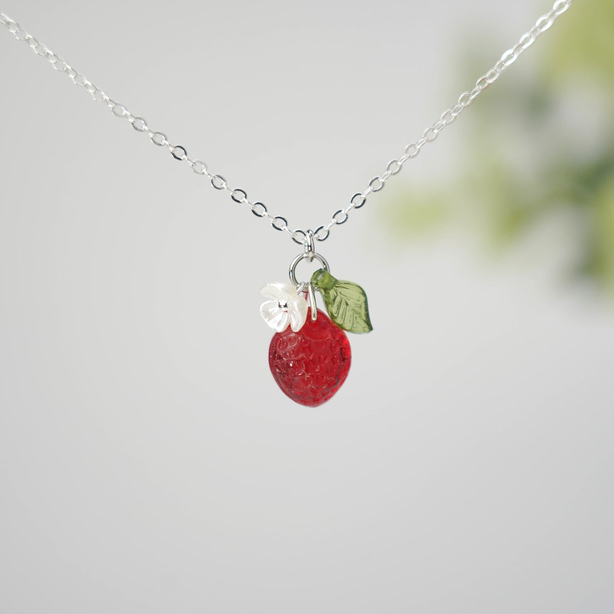 Silver mini strawberry pendant necklace with white flower and green leaf charm on chain