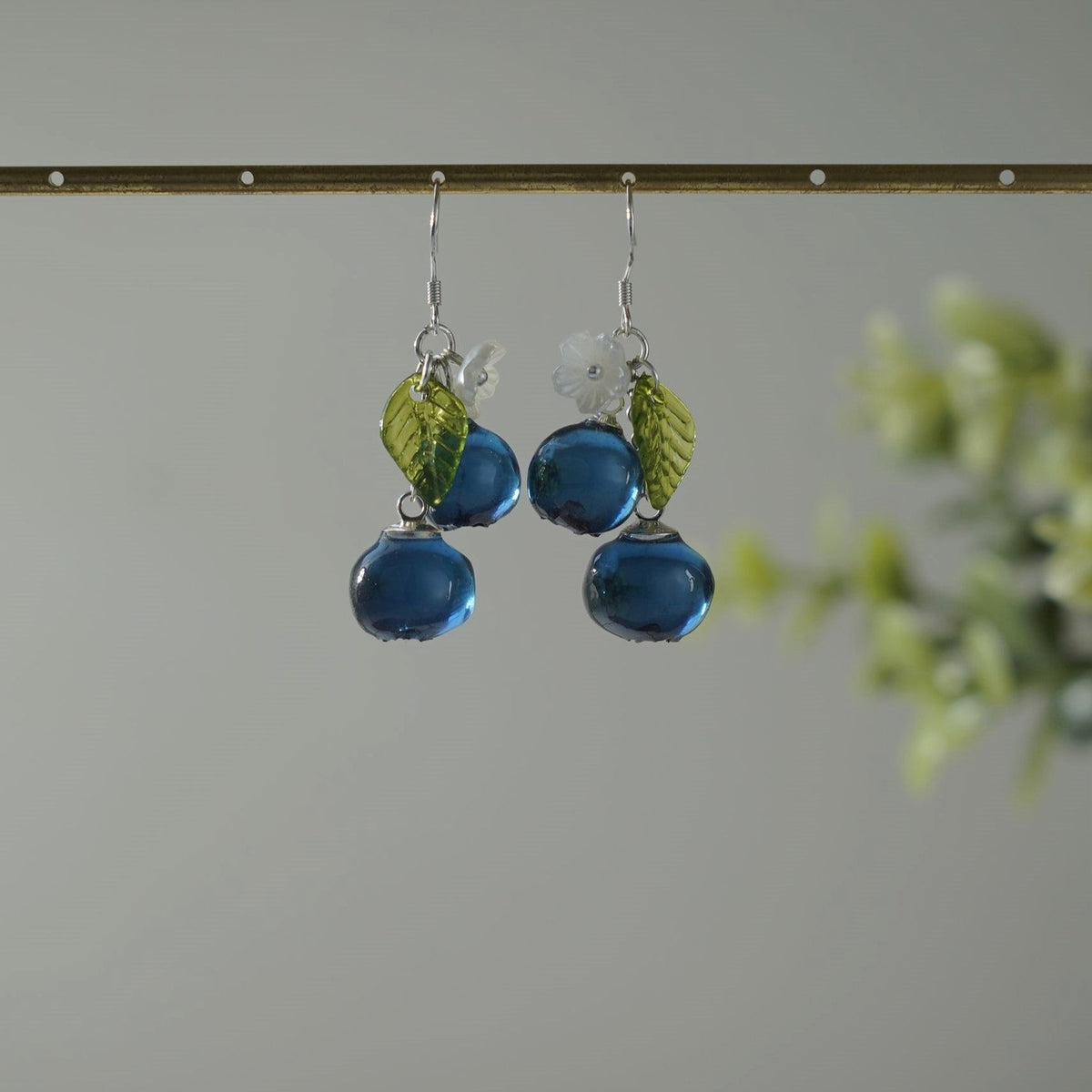 Blueberry cluster dangle earrings with blue resin berries, green leaves, and silver hooks