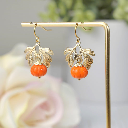 Gold-tone hanging pumpkin earrings with orange glass beads and leaf charms