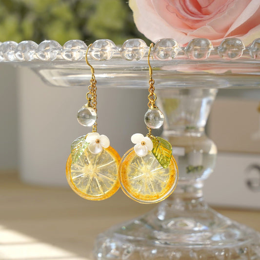 Gold-tone dangle earrings featuring lemon-kumquat slice resin charms with white flower details