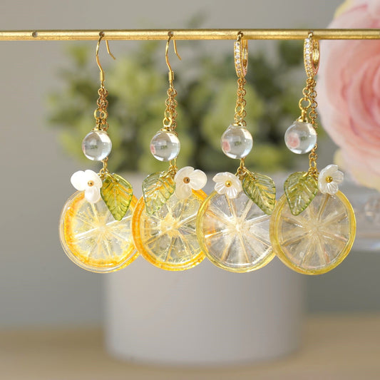 Gold-tone dangle earrings with lemon-kumquat slice resin charms, white flower tops, clear beads