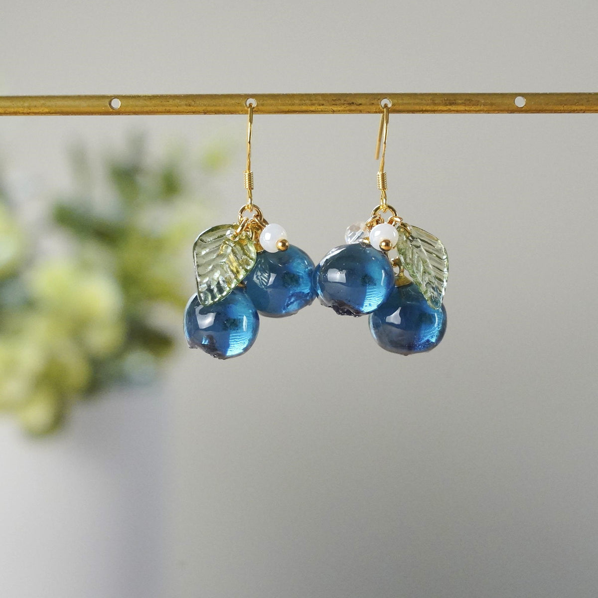 Blue resin berry cluster earrings with gold hooks and textured leaf charms
