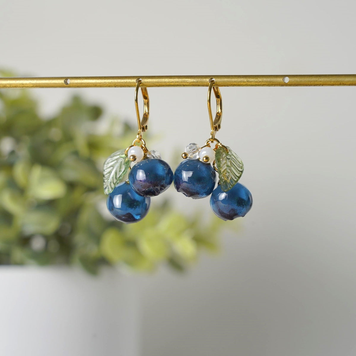 Blue resin berry cluster earrings with gold hooks, green leaf charms, small pearl