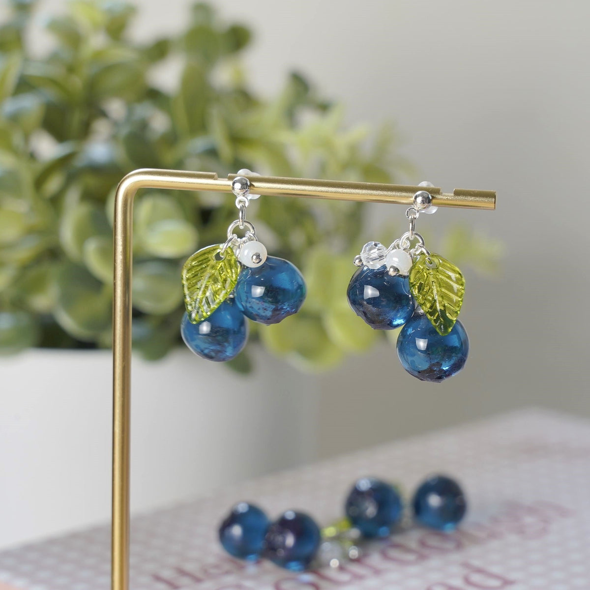 Blue resin berry cluster earrings with silver hooks and green leaf accents
