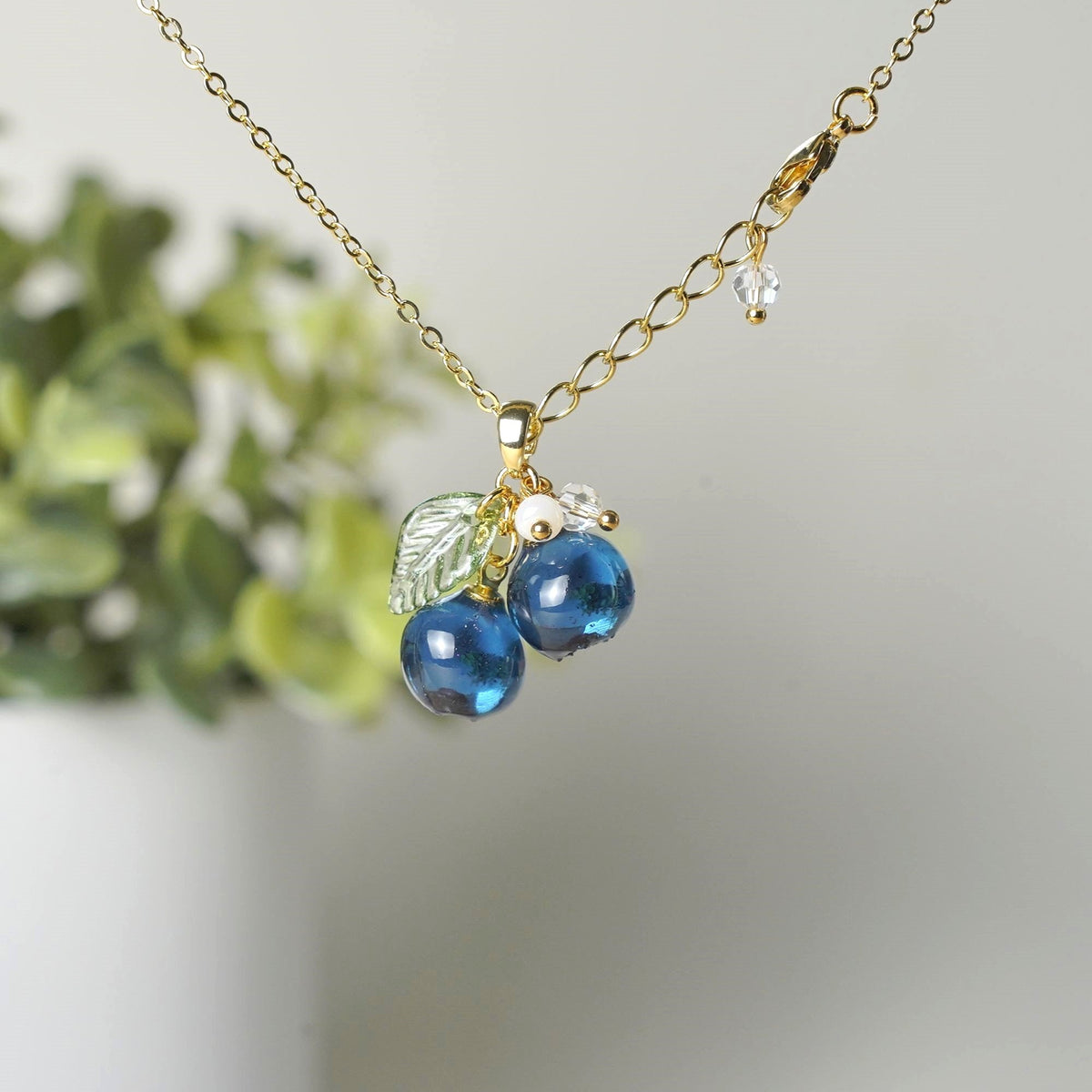 Gold blueberry fruit cluster necklace with resin berries, green leaves, and small bead drops
