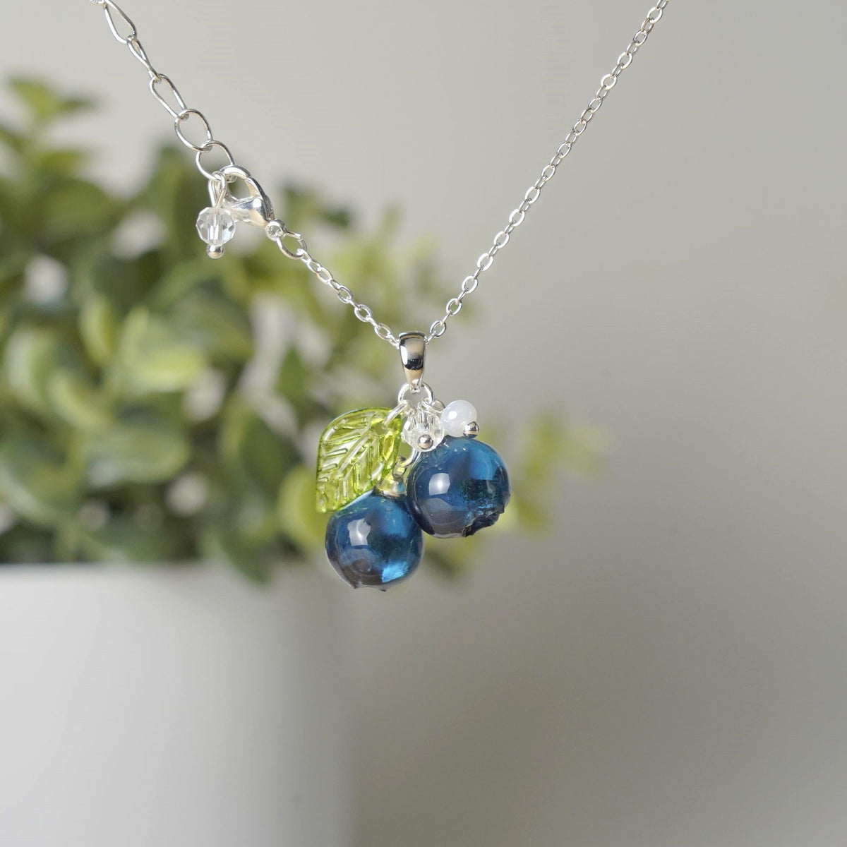 Silver blueberry cluster necklace with resin berries, green leaf accent, and bead charm