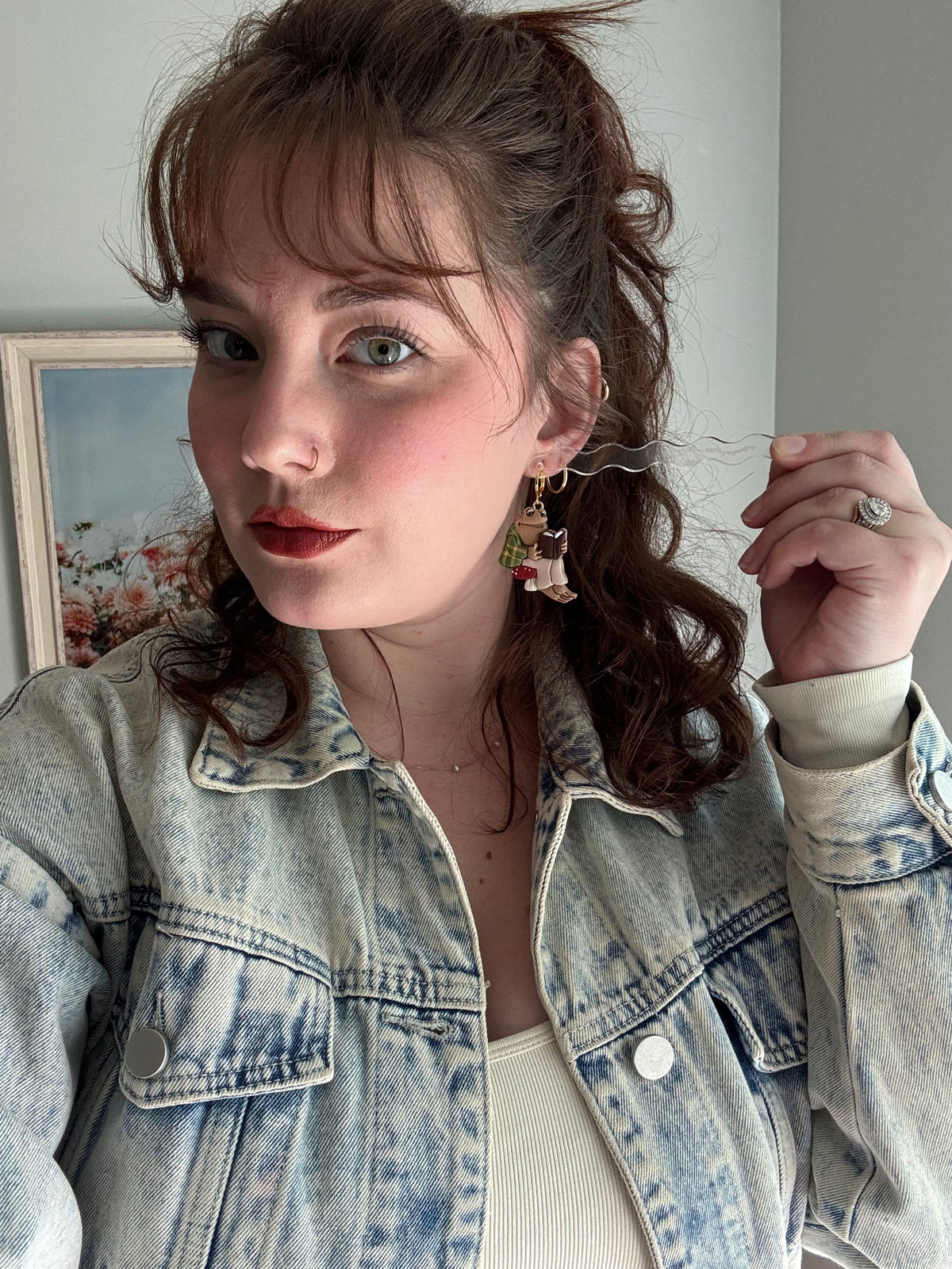 Dangling frog and toad charm earrings with multicolor details on a model