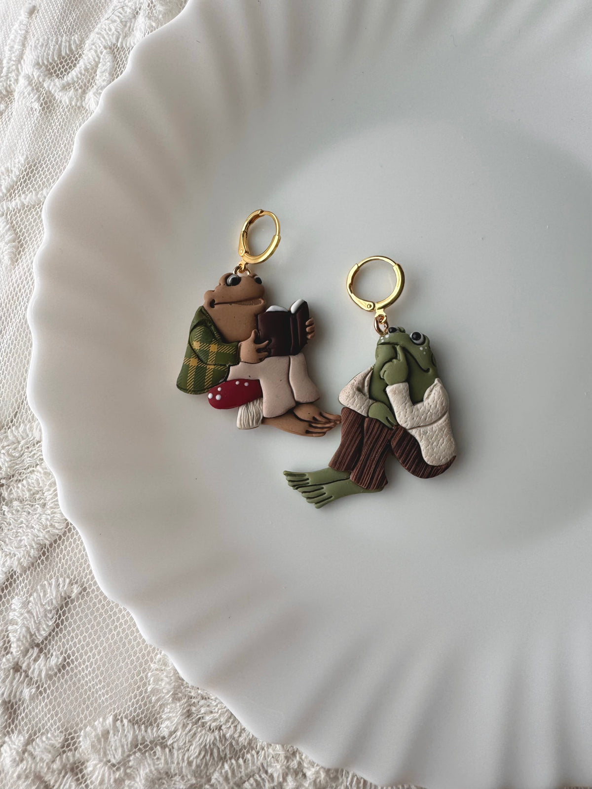 Two character keychains: frog and toad with gold rings and small outfit details