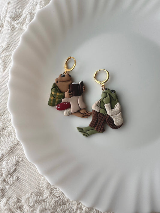 Two character keychains: frog and toad with gold rings and small outfit details