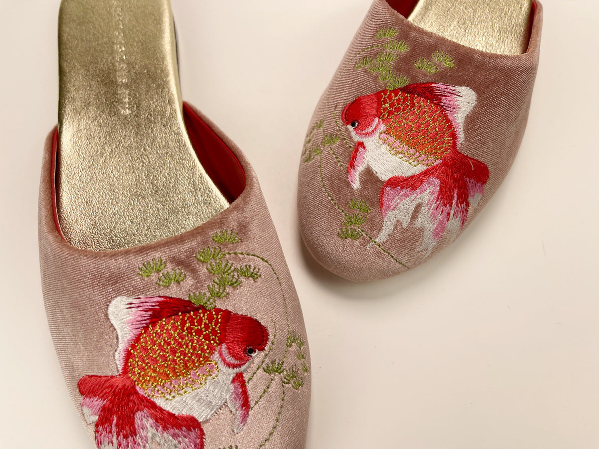 Two dusty pink velvet mule slippers with goldfish embroidery and open red lining