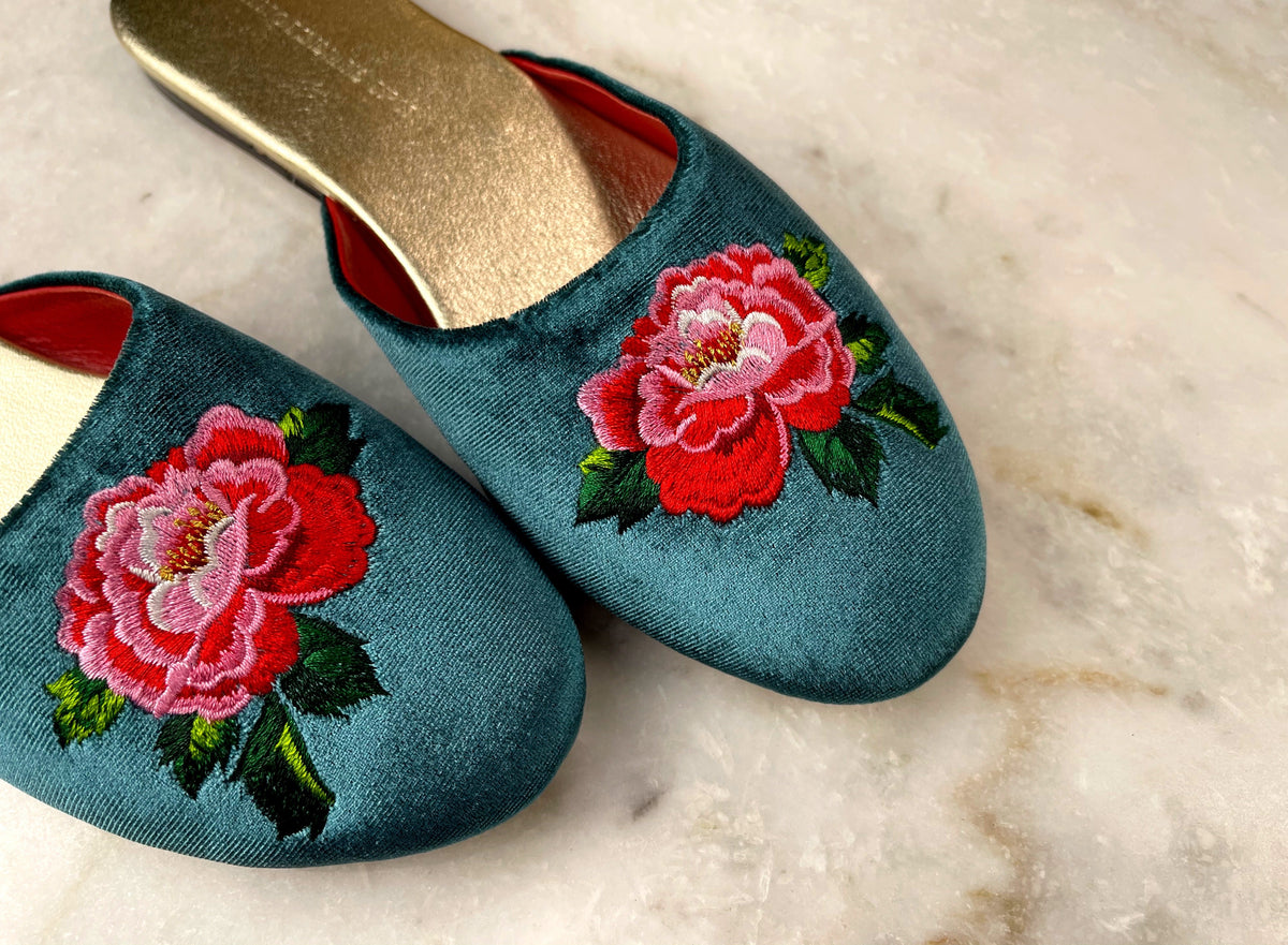Teal velvet mule slippers with red peony embroidery and gold-toned insoles, angled