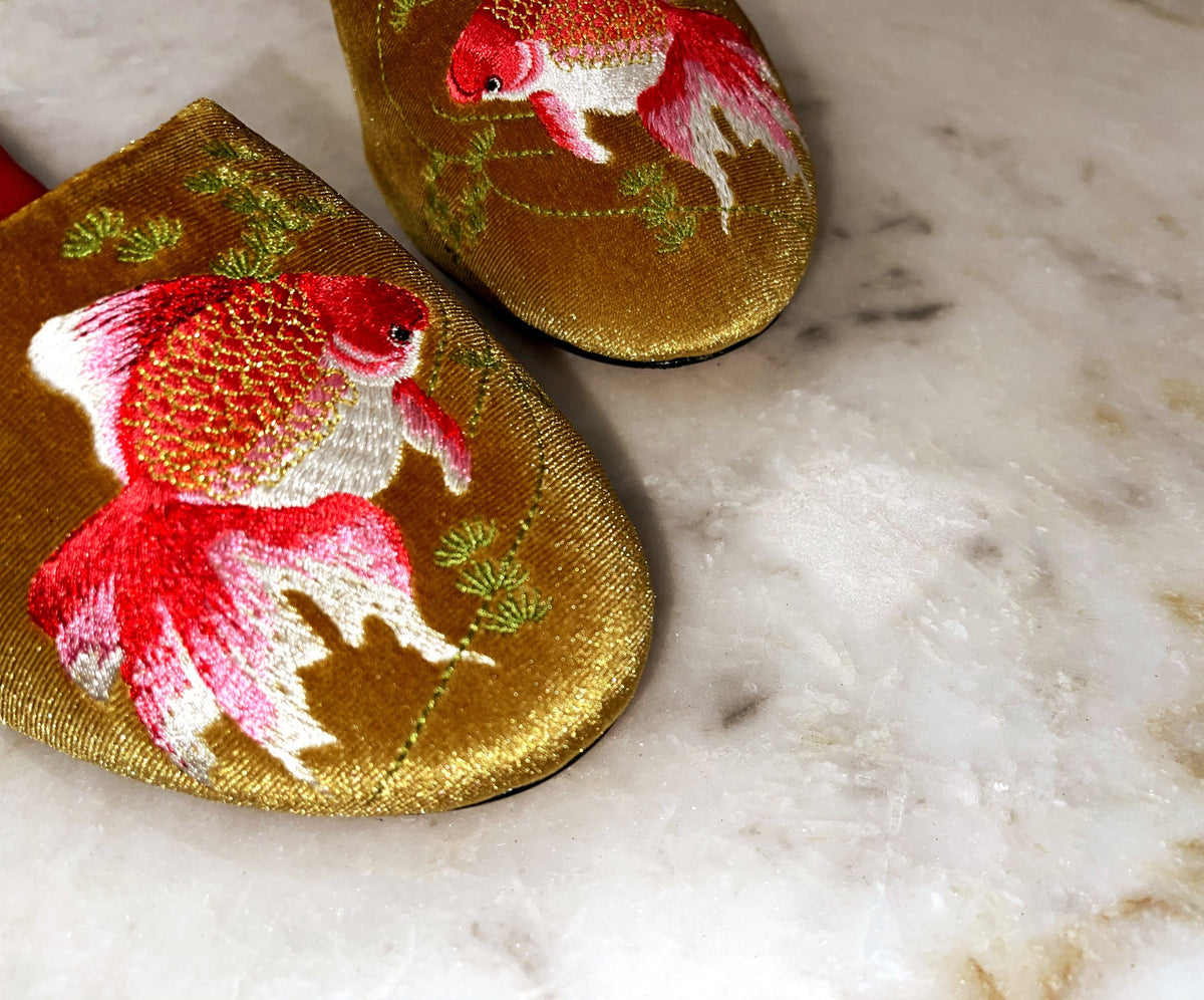 Gold velvet mule slippers close-up with red and white goldfish embroidery, pointed toe