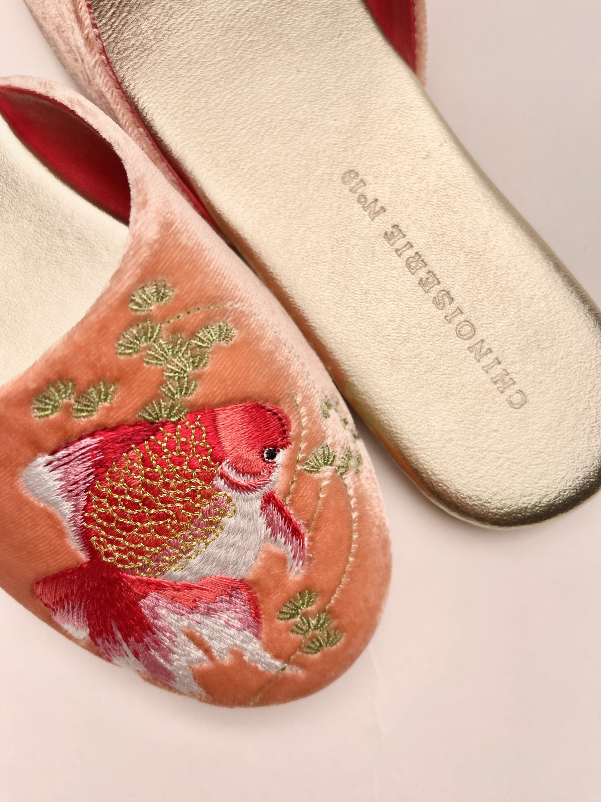 Close-up peach velvet mules with goldfish and green floral embroidery, suede insole