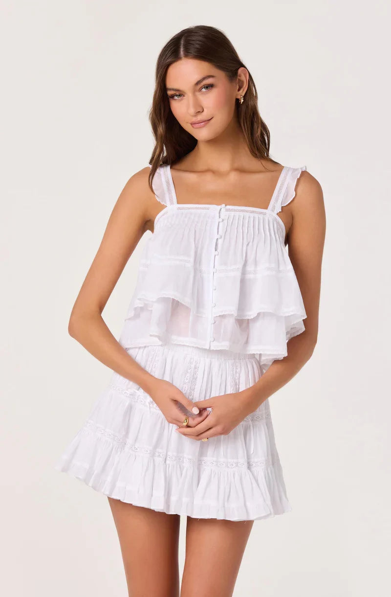 White tiered babydoll top with smocked front, layered ruffles, and thin straps