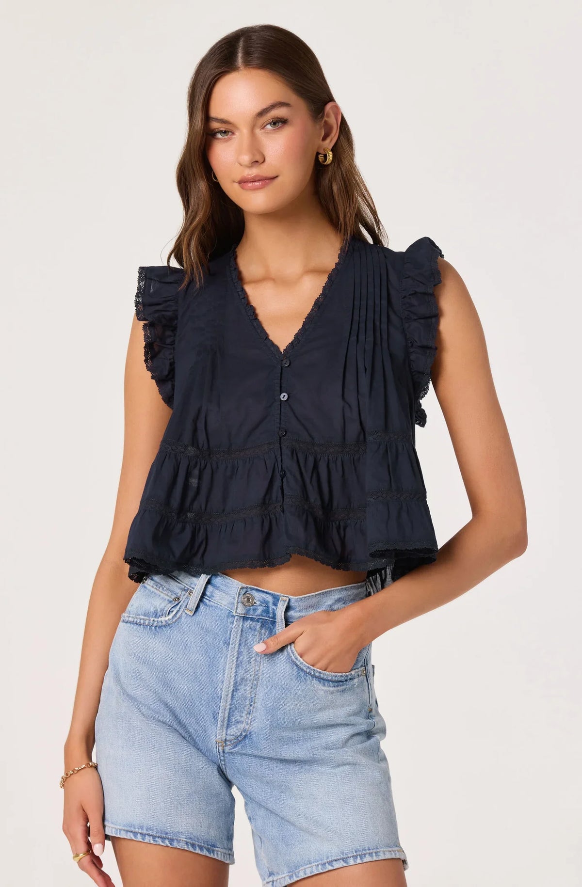 Navy sleeveless peplum-style top with V-neck buttons and tiered ruffles