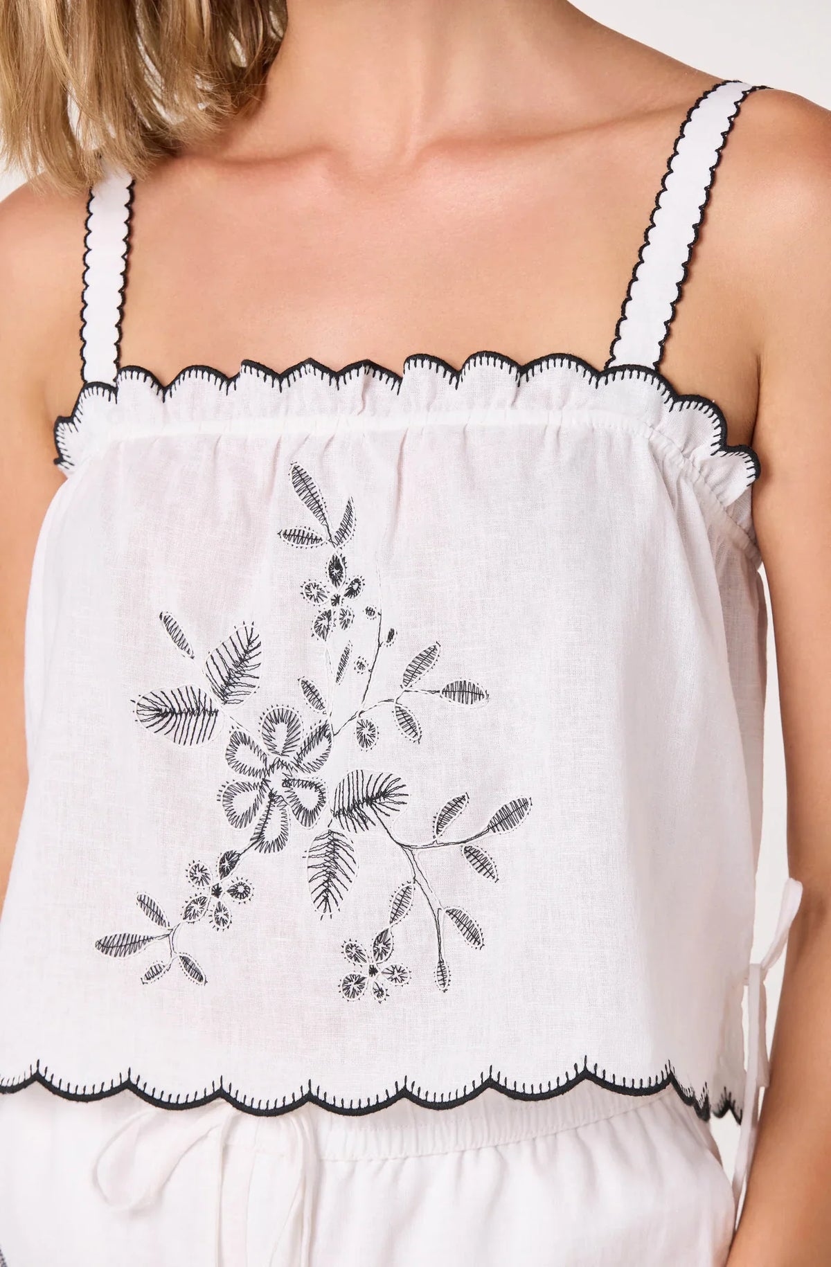 Off-white embroidered camisole top close-up with scalloped trim and spaghetti straps