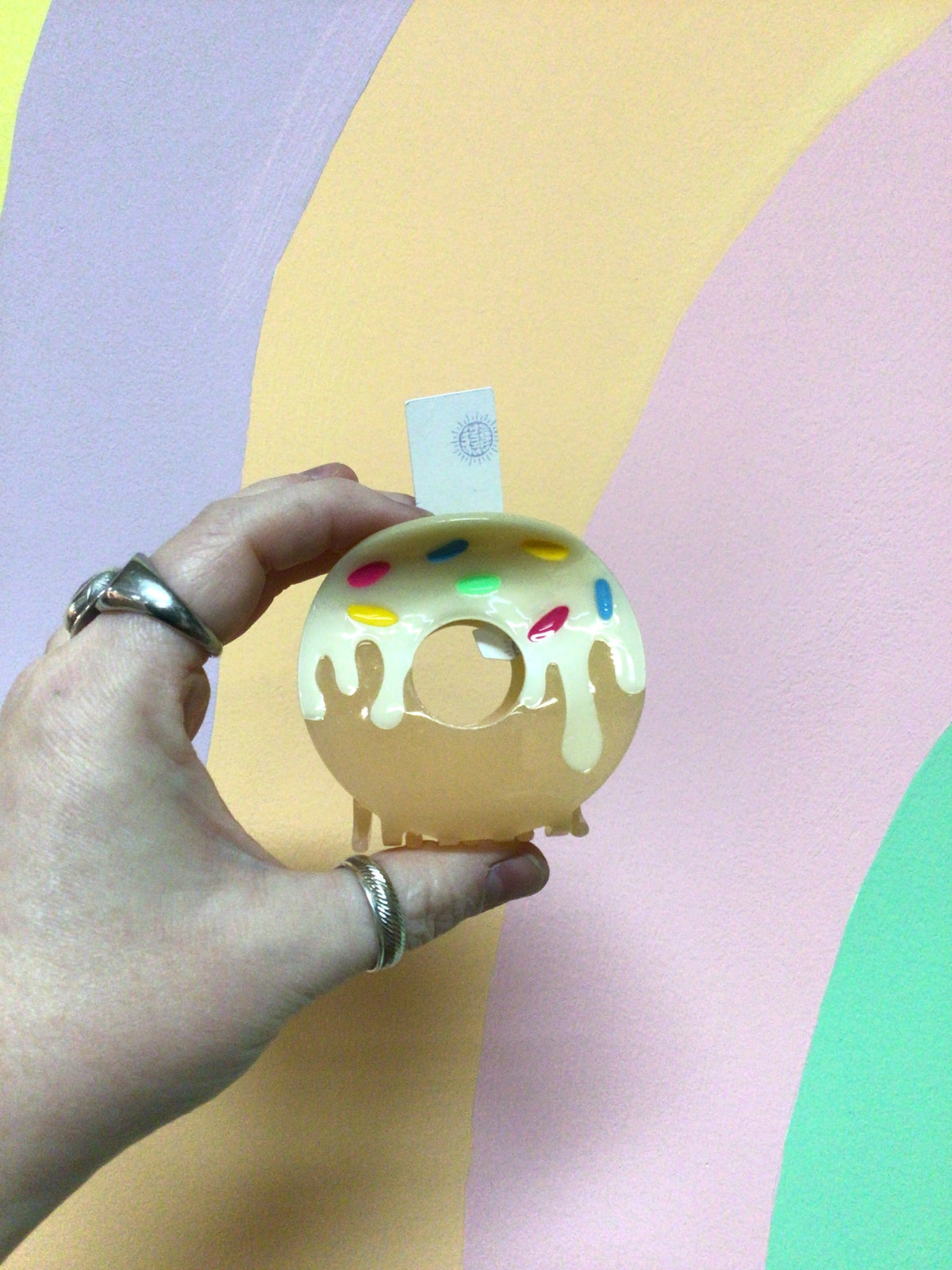 Donut-shaped hair claw with light beige frosting and yellow sprinkle details